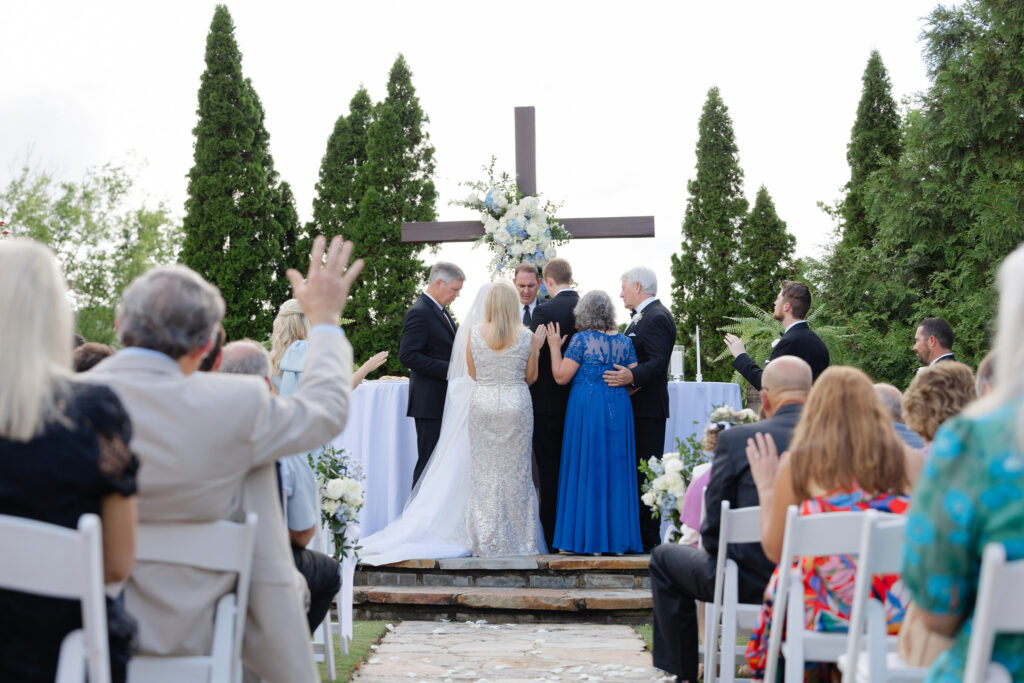 Family praying over bride and groom at wedding ceremony