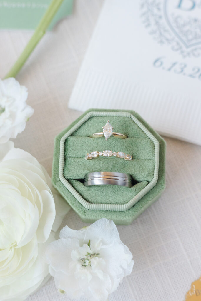 Wedding rings in a green velvet ring box surrounded by white flowers