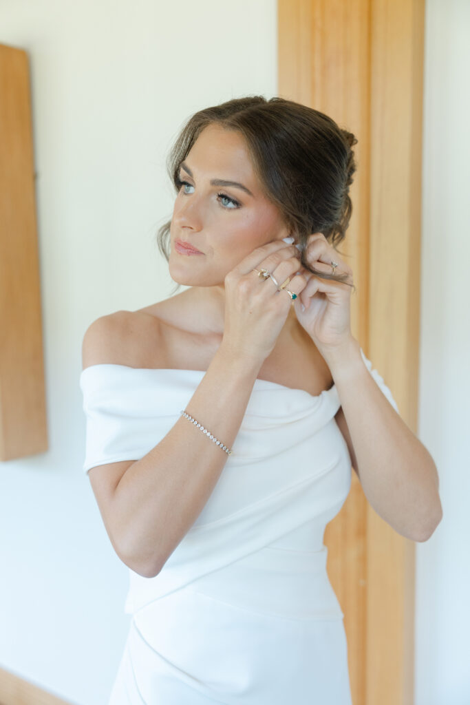 Brooke putting on pearl earrings before her wedding ceremony