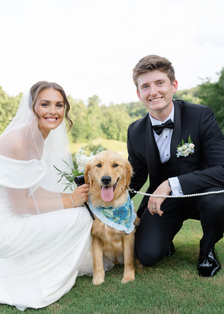 Brooke and Zach with her golden retriever wearing a blue and green floral bandana on her wedding day