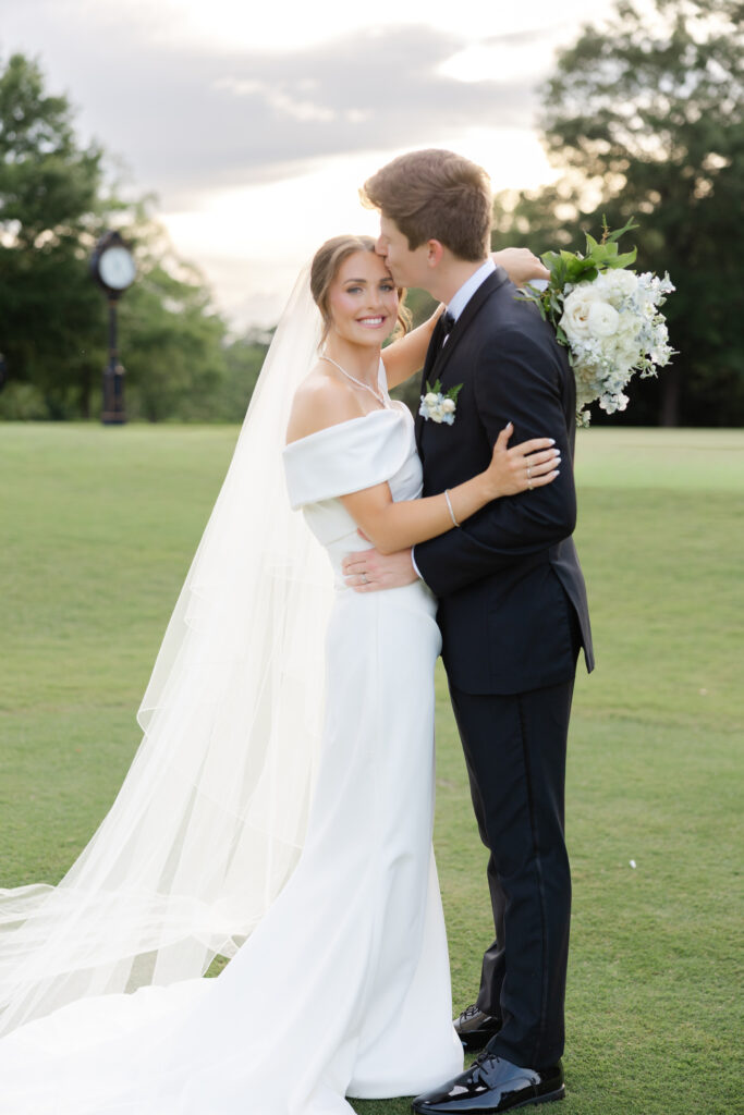 Zach kissing Brooke's forehead during portraits at Old Overton Country Club